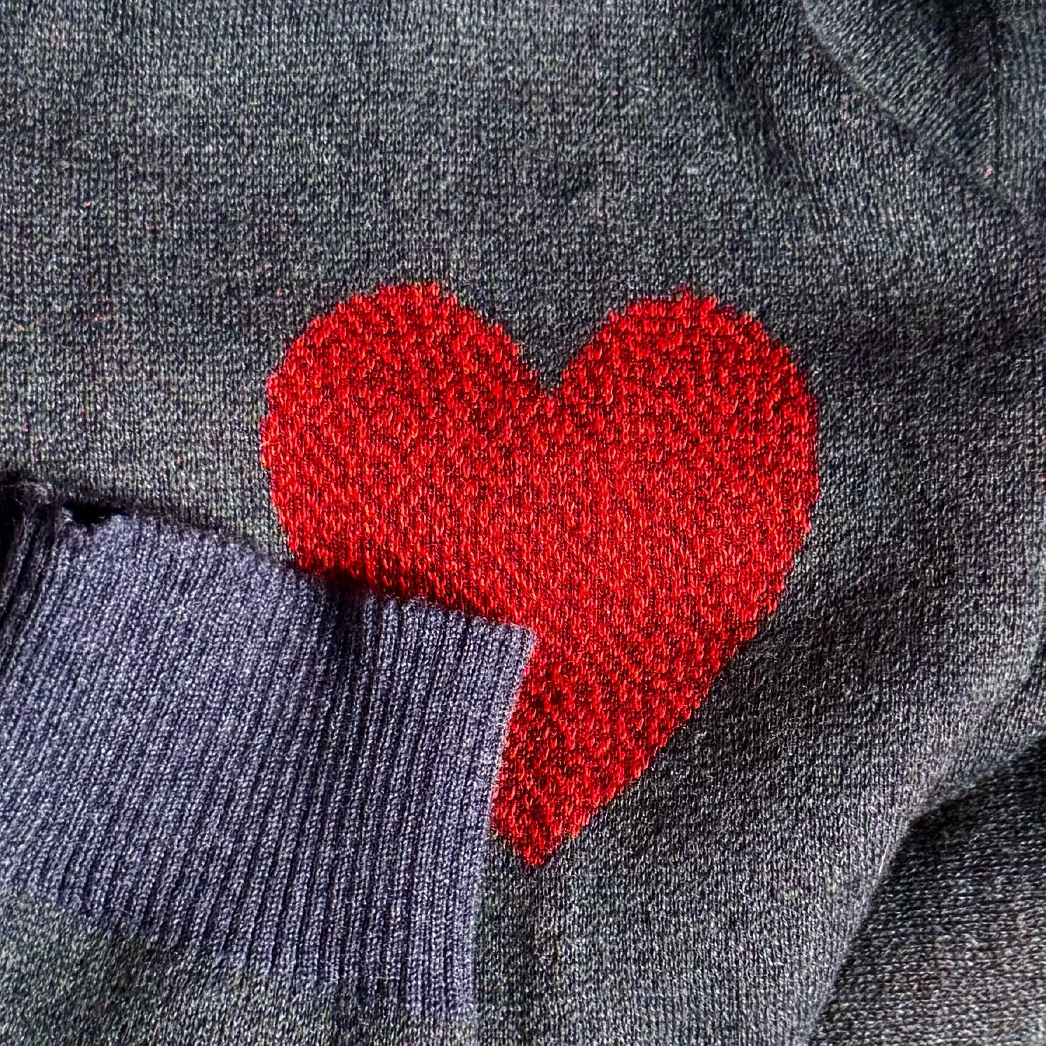 Detail shot of the knitted heart motif on the deep sea blue Heart On My Sleeve sweater by Jedd