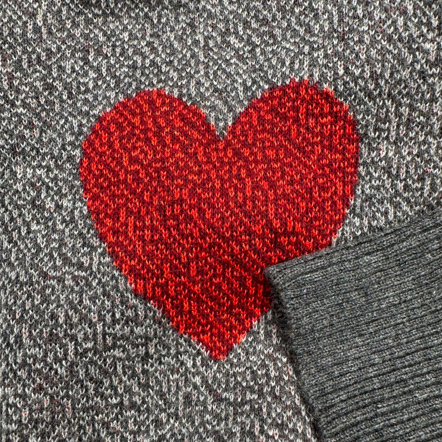 Detail of the knitted heart sleeve design on the gray Heart On My Sleeve graphic knit sweater by Jedd