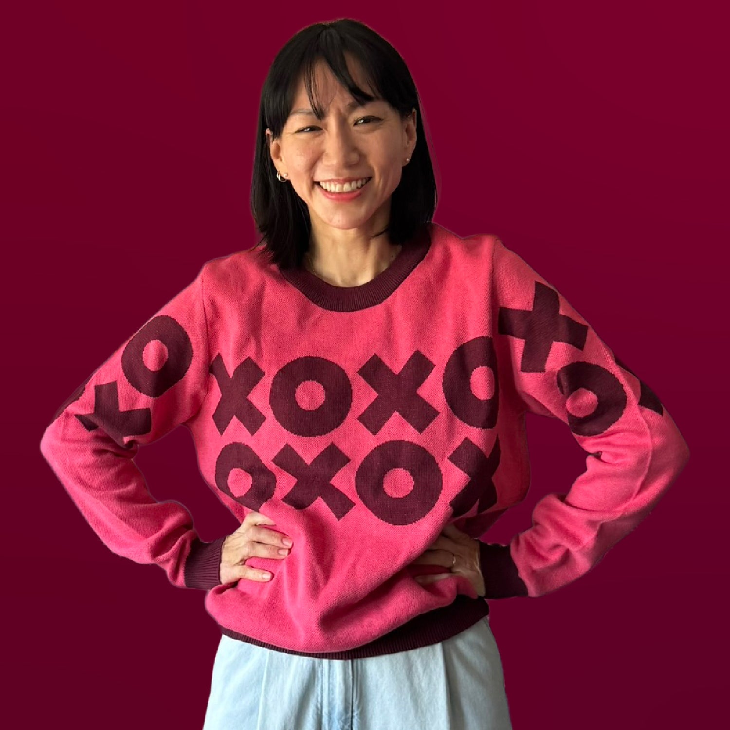 Person wearing a pink sweater with 'xoxo' prints on a red background