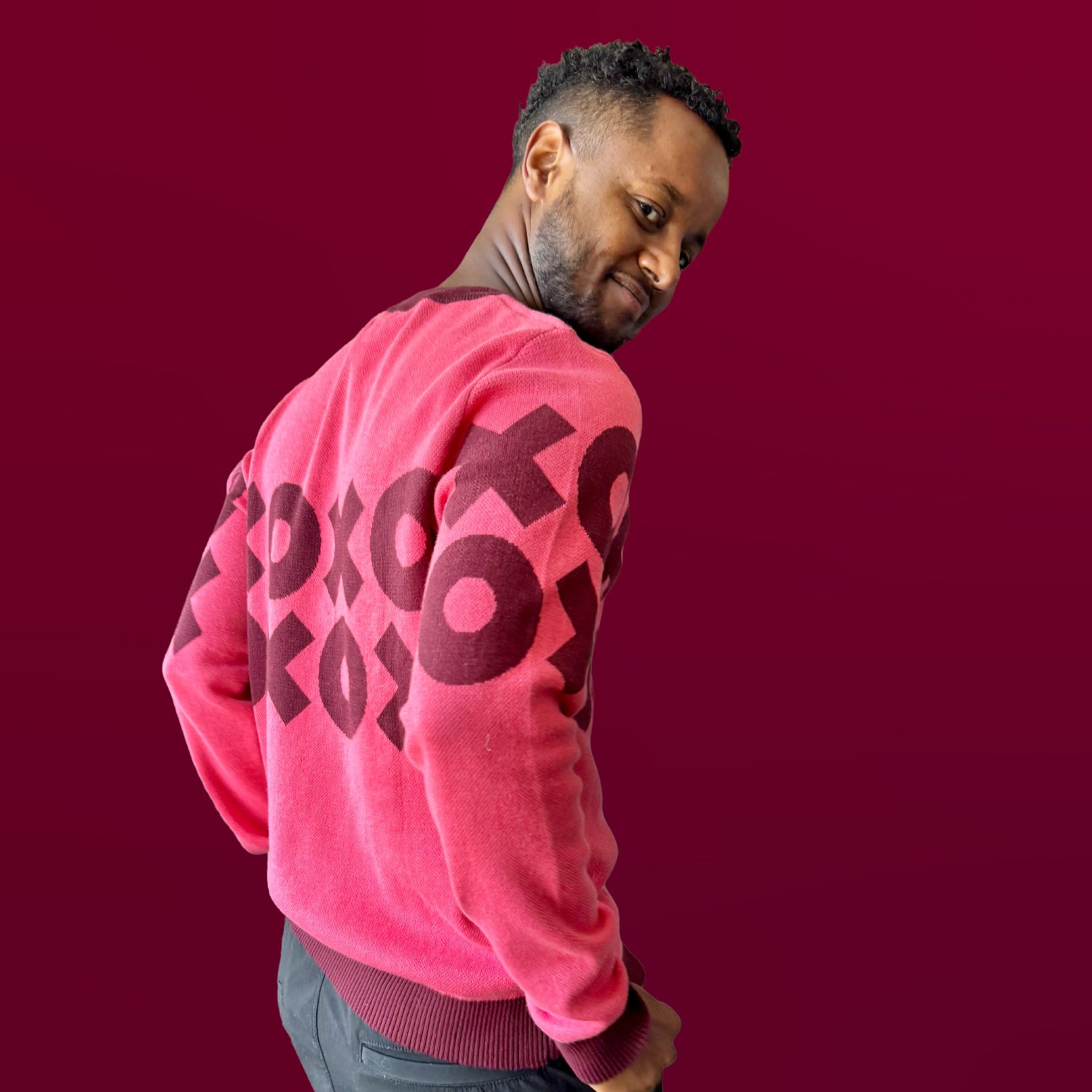 Man wearing a pink sweater with red text on a red background