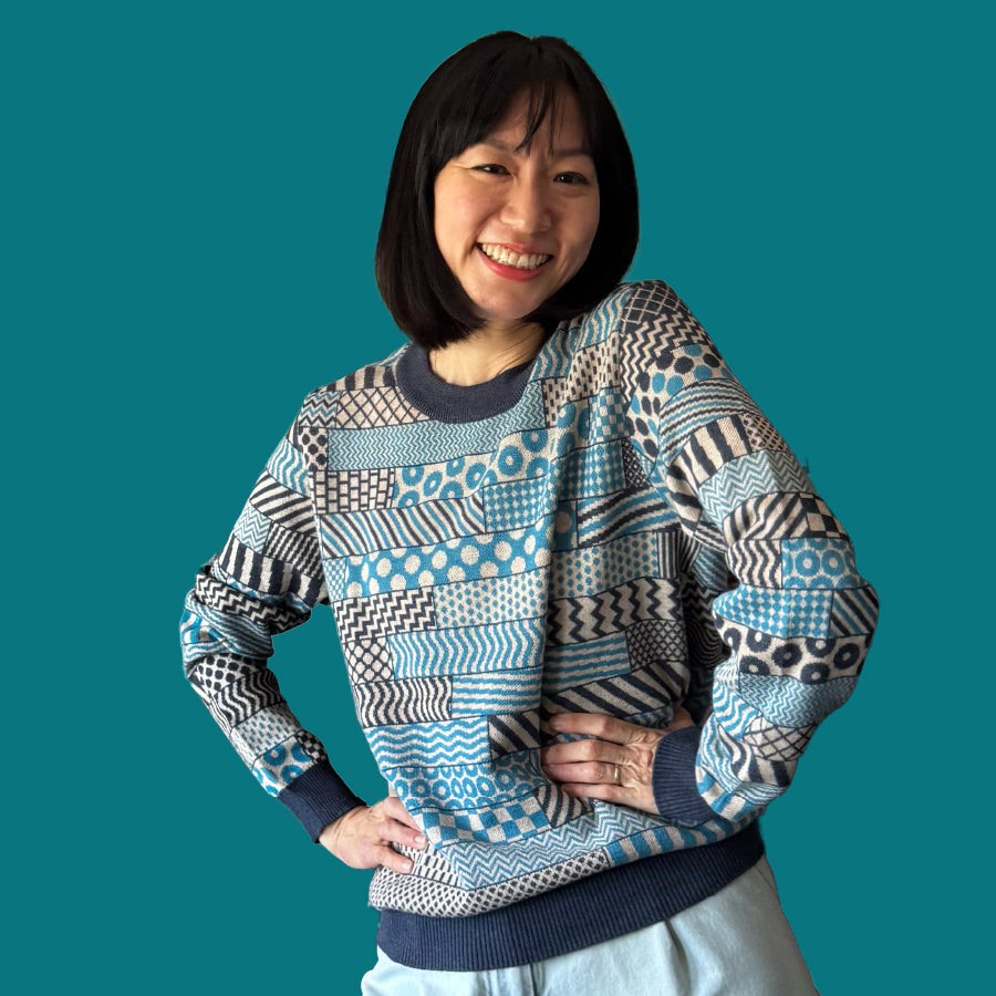 A woman wearing a blue sweater with detailed geometric patterns