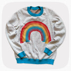 A gray graphic knit sweater with a sprinkled pattern and a rainbow on the front center.