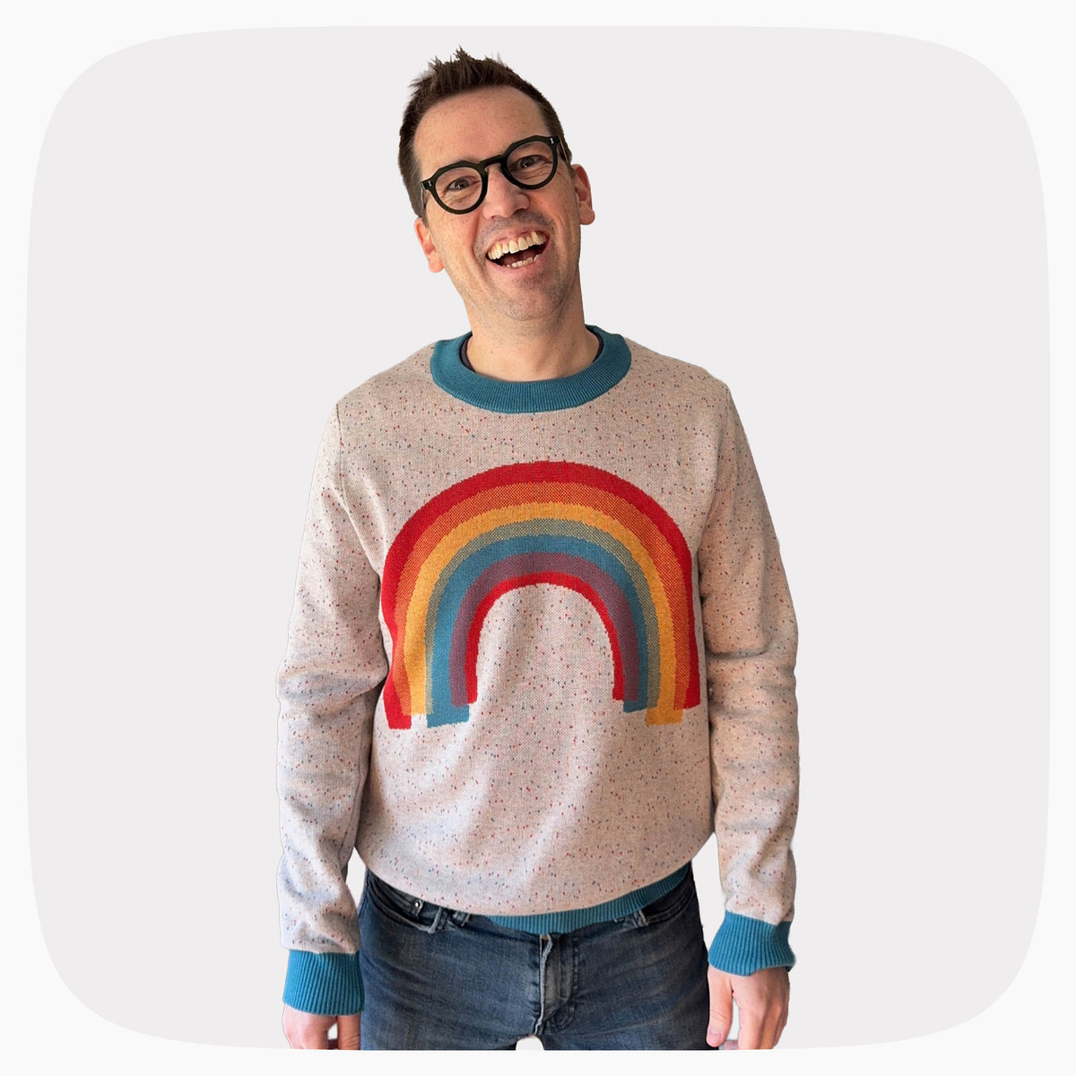 Jedd wearing a gray graphic knit sweater with a sprinkled pattern and a rainbow on the front center.