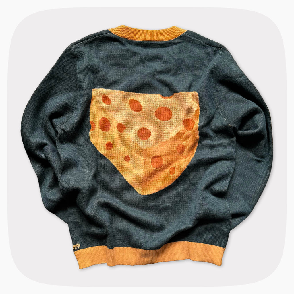 The back of a green graphic knit sweater with a big piece of cheese design on the center.