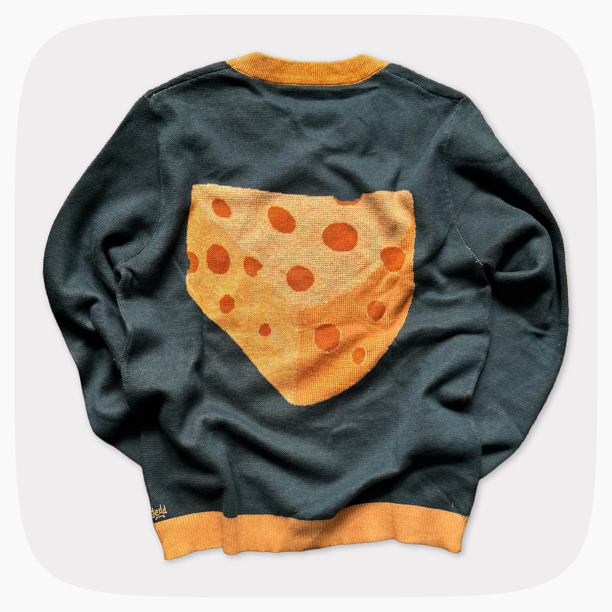 The back of a green graphic knit sweater with a big piece of cheese design on the center.