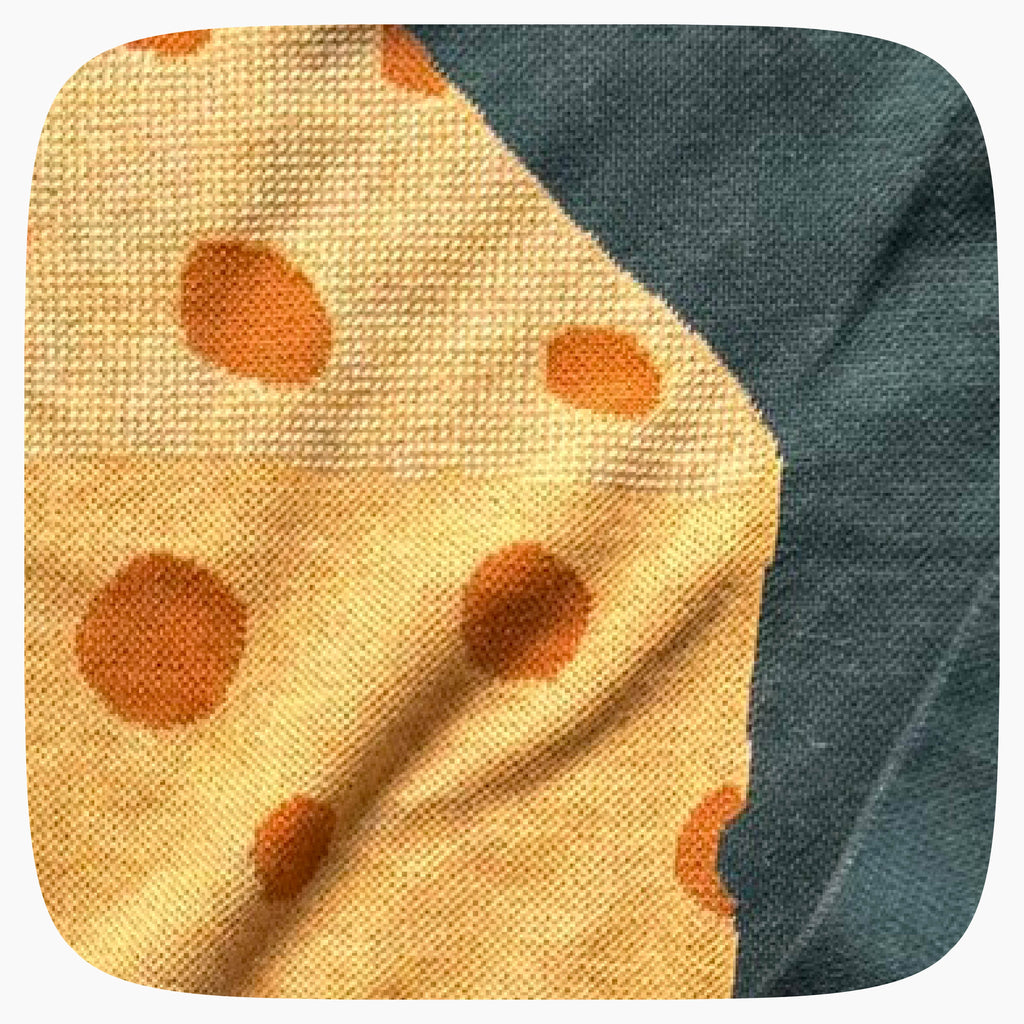 The detail of a green graphic knit sweater with a big piece of cheese design on the center.