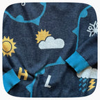 Detail of the pattern on a blue graphic knit sweater with weather forecast shapes like the sunny, clouds, and snowflakes.