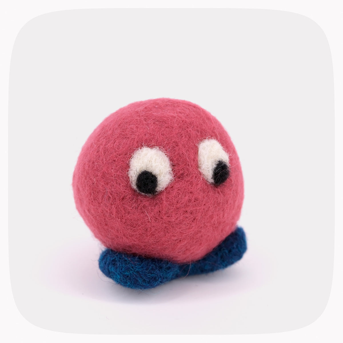 A red felted ball with eyes looking down and blue feet.
