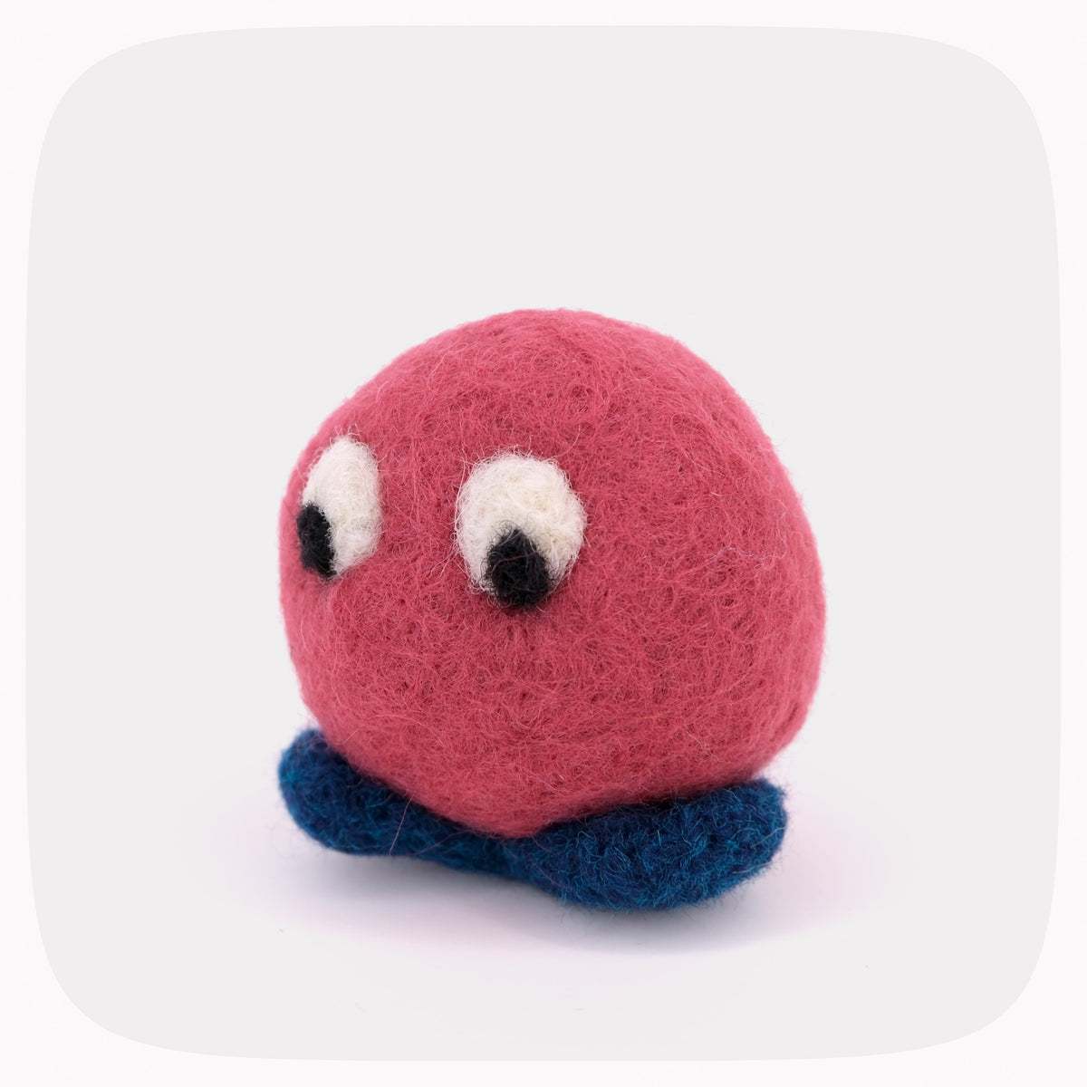 A red felted ball with eyes looking down and blue feet.