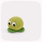 A green felted ball with eyes looking down and darker green feet.