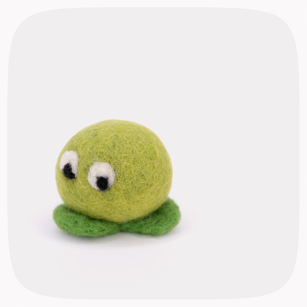 A green felted ball with eyes looking down and darker green feet.