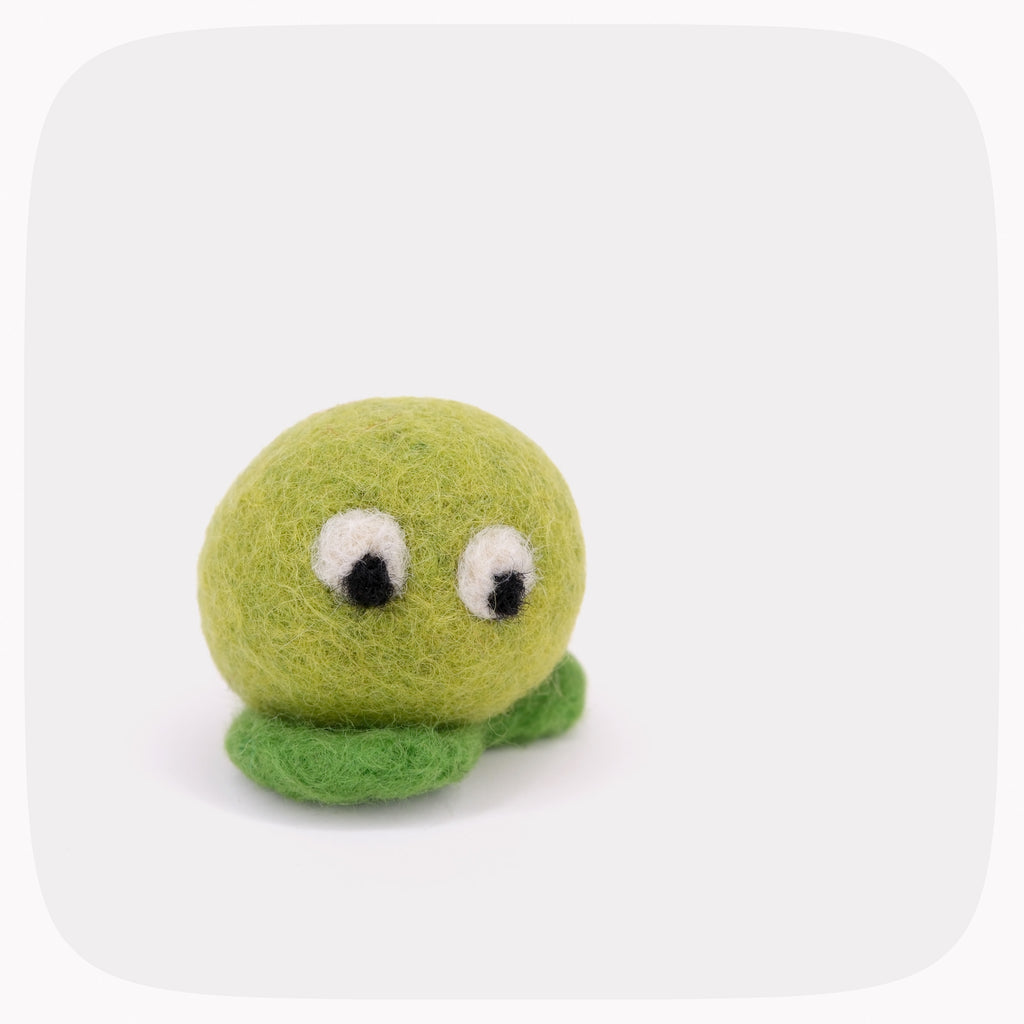 A green felted ball with eyes looking down and darker green feet.