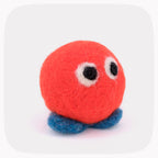 An orange felted ball with eyes and blue feet.