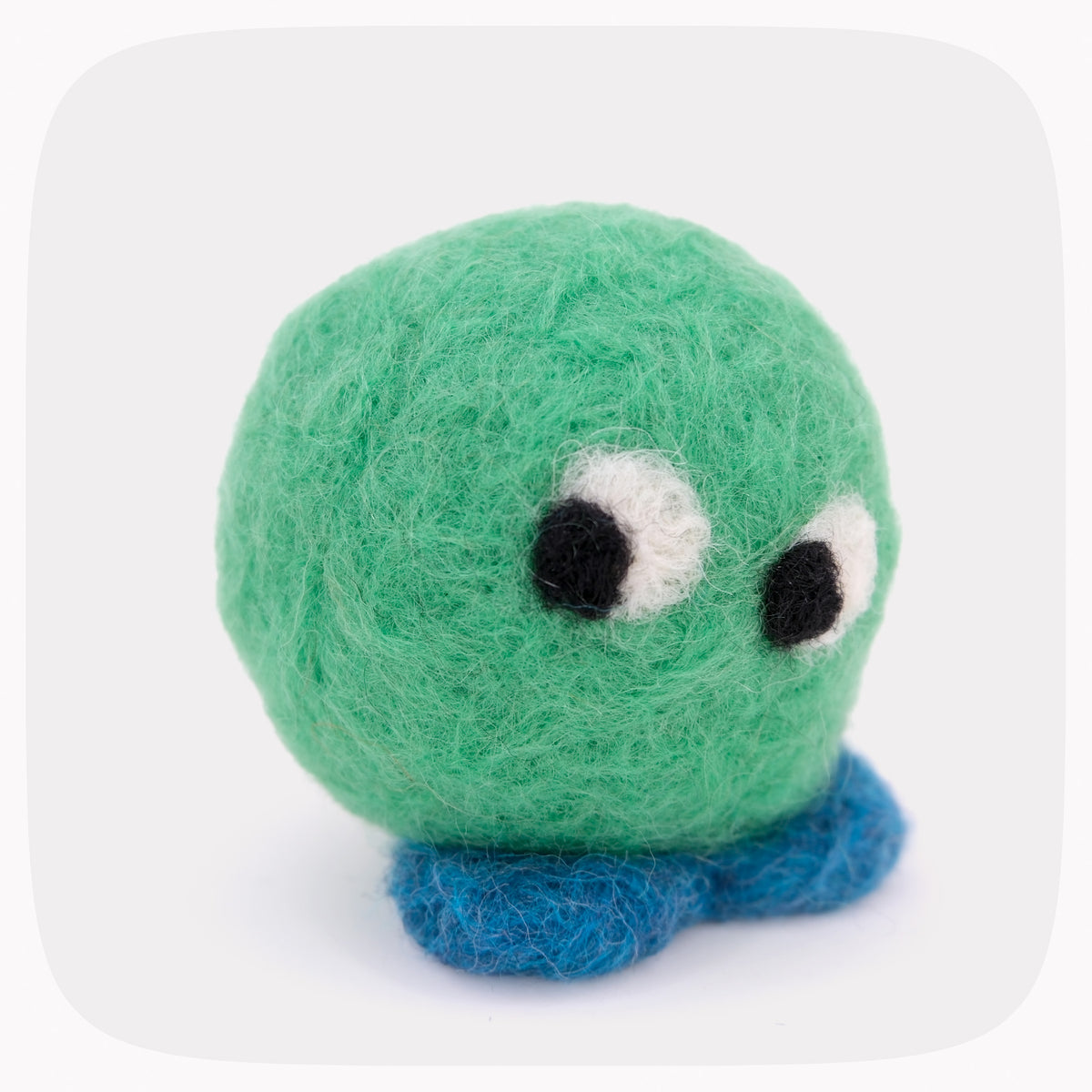 A green felted ball with eyes looking left and blue feet.