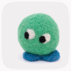 A green felted ball with eyes looking left and blue feet.