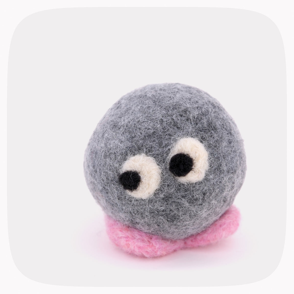 A gray felted ball with eyes looking left and pink feet.