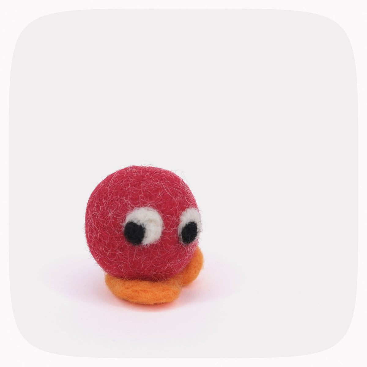 A small felt toy with a red round body, orange feet, and large white-and-black eyes, centered on a light gray background with rounded corners.