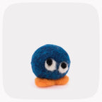 A small felted wool toy character with a round blue body, white and black eyes, and an orange beak or foot, centered on a light gray rounded-square background.