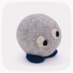 A small felted wool plush toy with a round gray body, two large cream and black eyes, and a dark blue foot, shown on a light gray background.