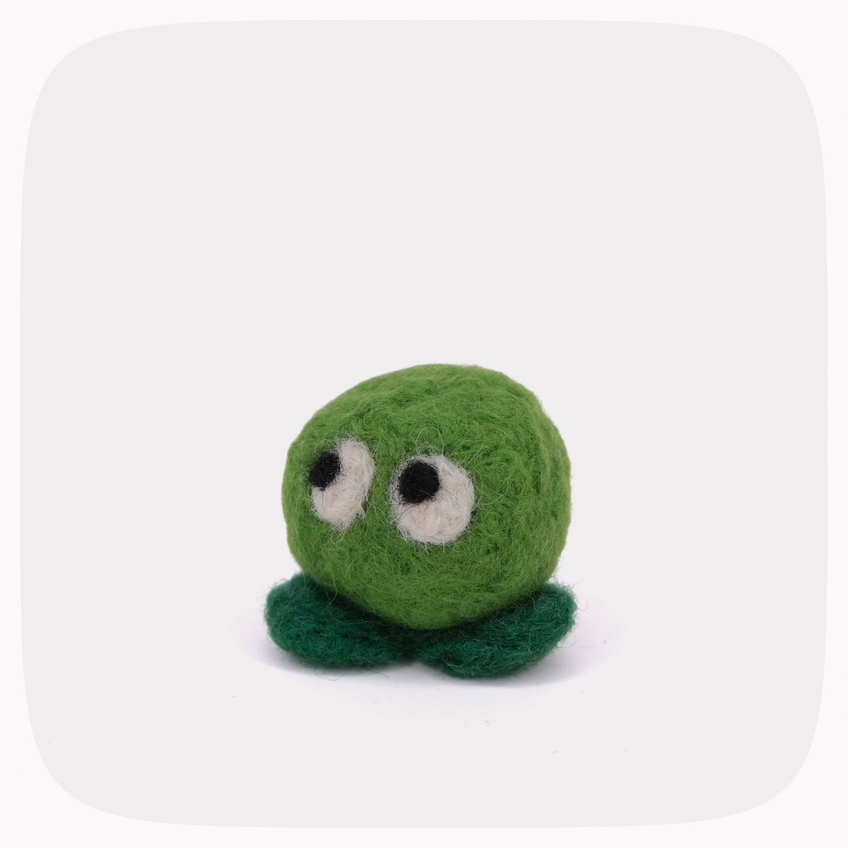 A small green felt plush toy with a round body, two dark green feet, and large white-and-black eyes, centered on a light gray background with rounded corners.