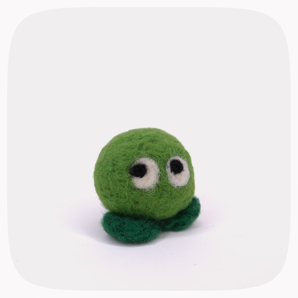 A small green felt plush toy with a round body, two dark green feet, and large white-and-black eyes, centered on a light gray background with rounded corners.