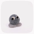 A small felted wool toy in shades of gray with black and white eyes, photographed on a clean white background with rounded corners.