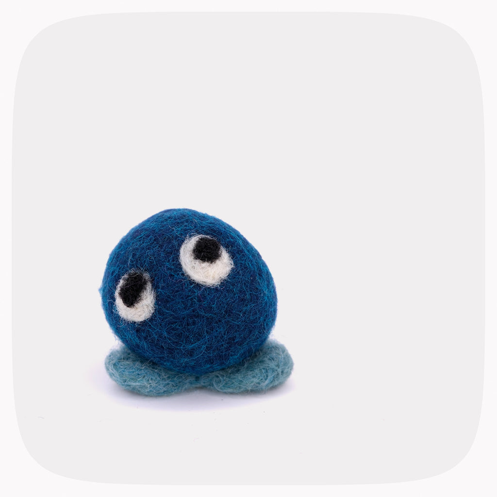 A small blue felt plush toy with a round fuzzy body, two large white-and-black embroidered eyes, and two short blue felt feet, shown on a light gray background.