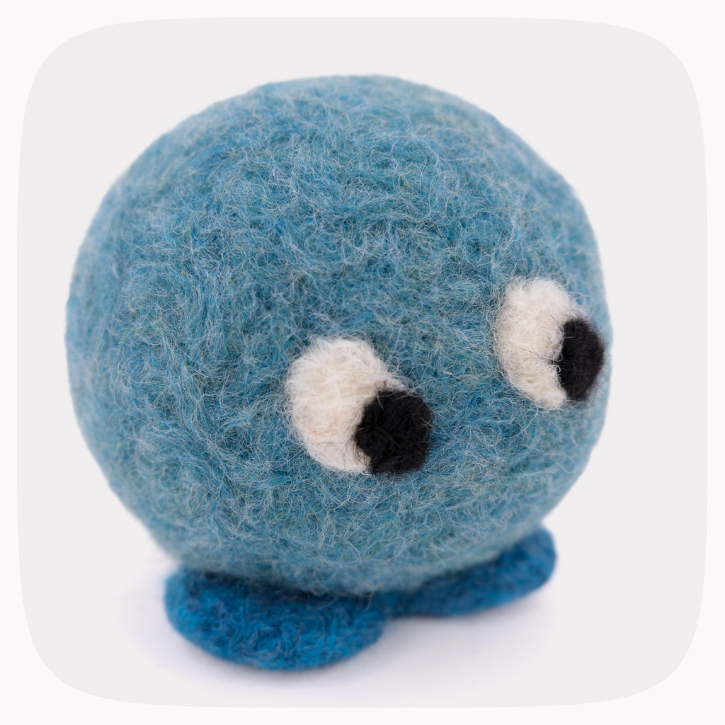 A small blue felt plush toy with a round fuzzy body, two large white-and-black embroidered eyes, and two short blue felt feet, shown on a light gray background.