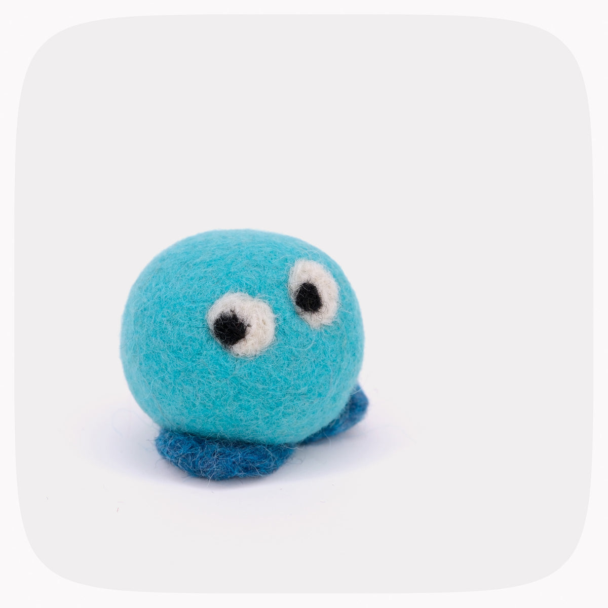 A small felt toy in bright turquoise blue with dark blue feet, white and black eyes, and white felt cheeks, photographed on a light gray background with rounded corners.