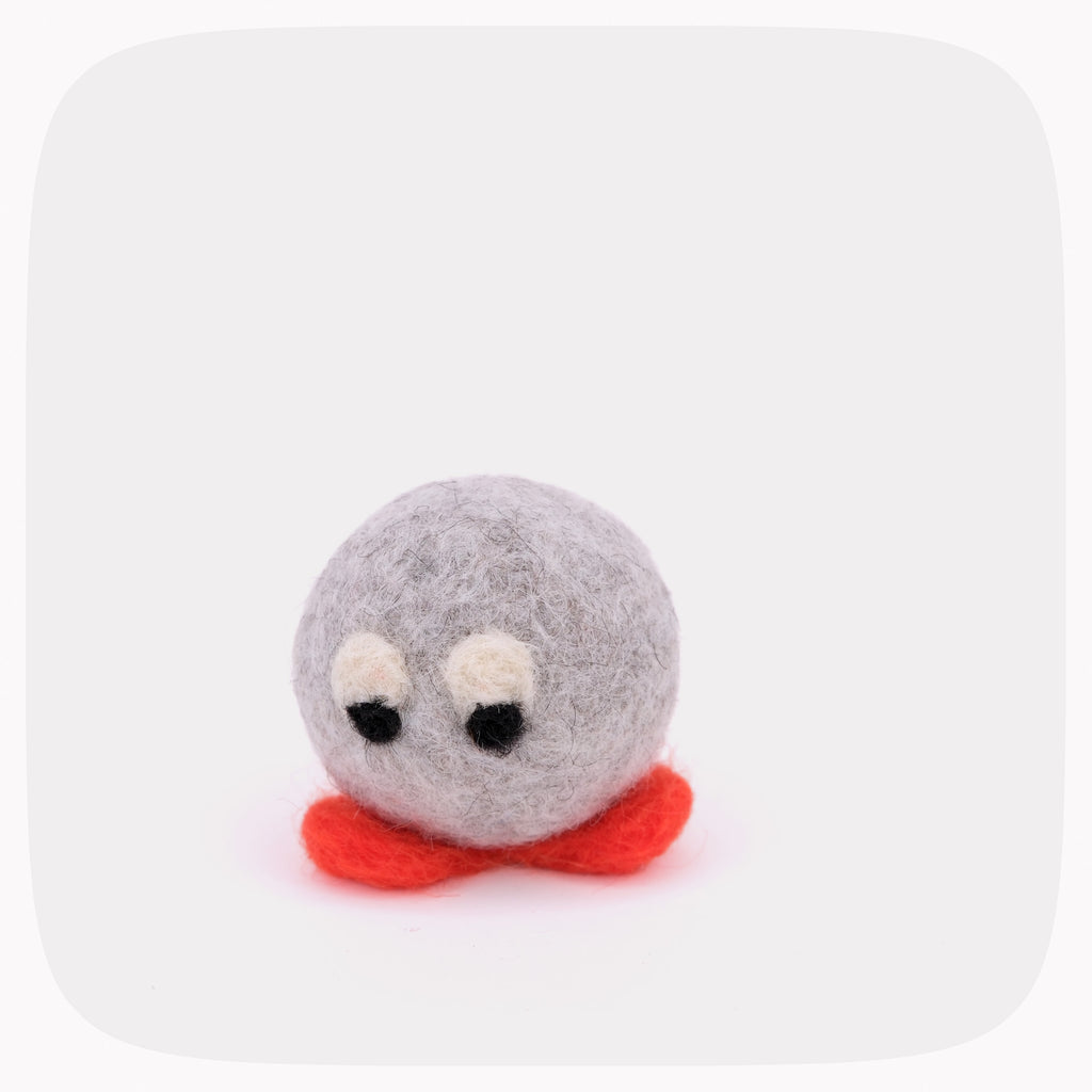 A small felted wool plush toy with a round gray body, white eyes with black pupils, and a bright red base, centered on a light gray background.