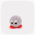 A small felted wool plush toy with a round gray body, white eyes with black pupils, and a bright red base, centered on a light gray background.