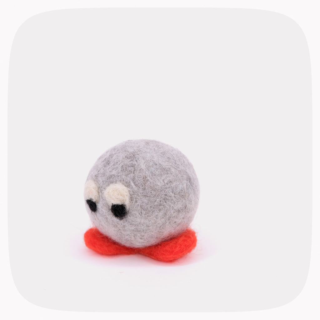 A small felted wool character toy with a round gray body, black and white eyes, and bright red feet, centered on a light gray background.
