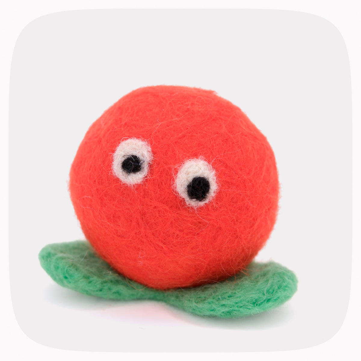 A bright orange felted ball with green feet and eyes.