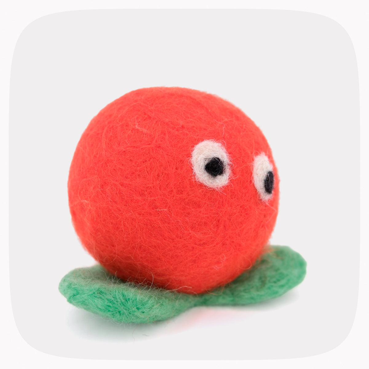 A bright orange felted ball with green feet and eyes.
