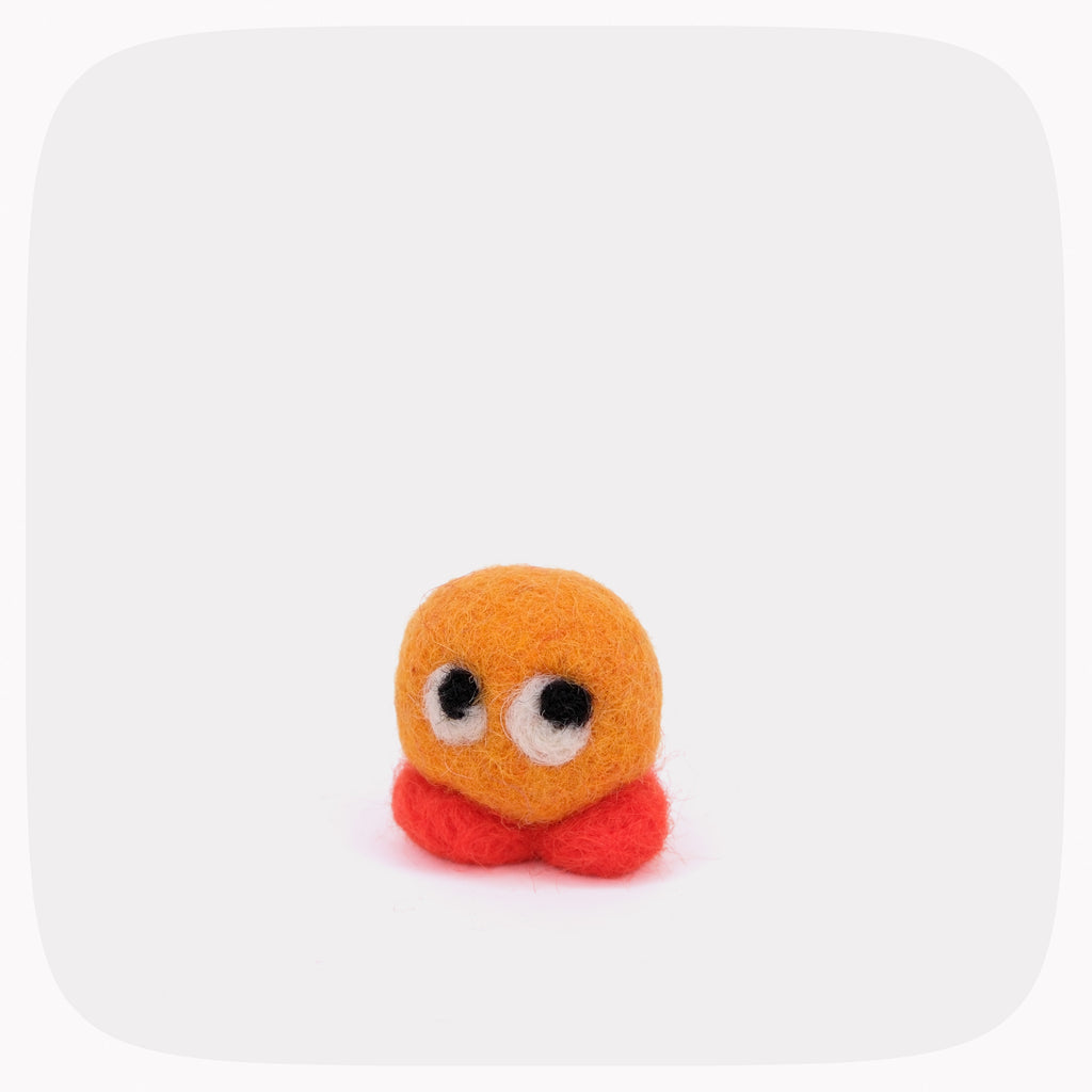 A small felt toy character with a round orange head, large white eyes with black pupils, and red feet, centered on a light gray background with rounded corners.