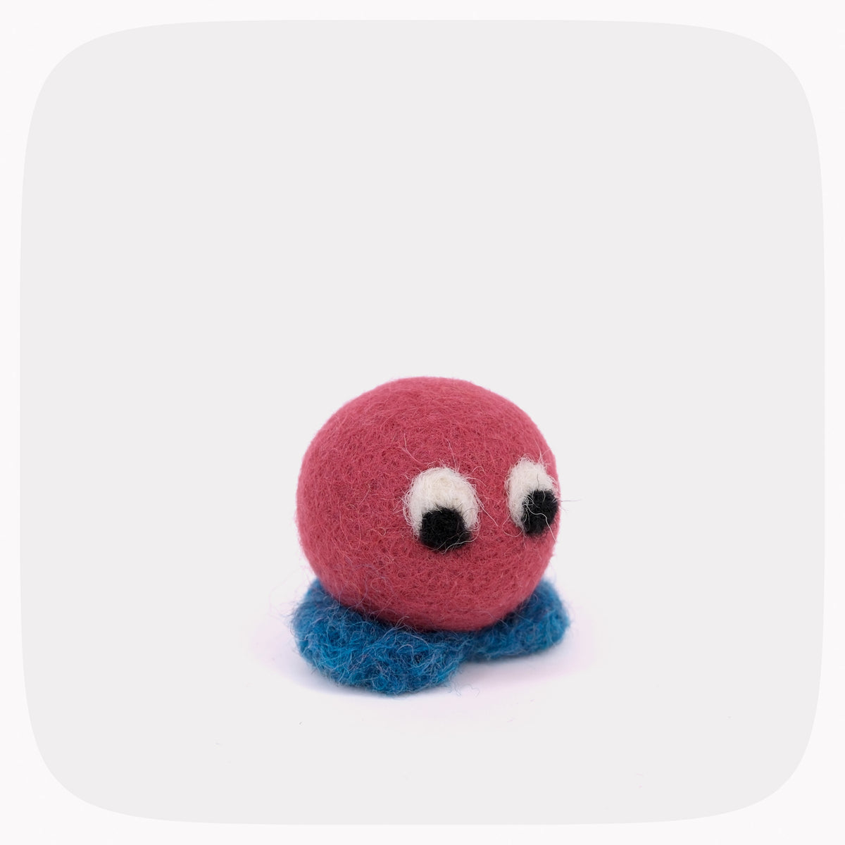 A small felt toy character with a round pink head, blue base, and large googly-style eyes, centered on a light gray rounded-square background.