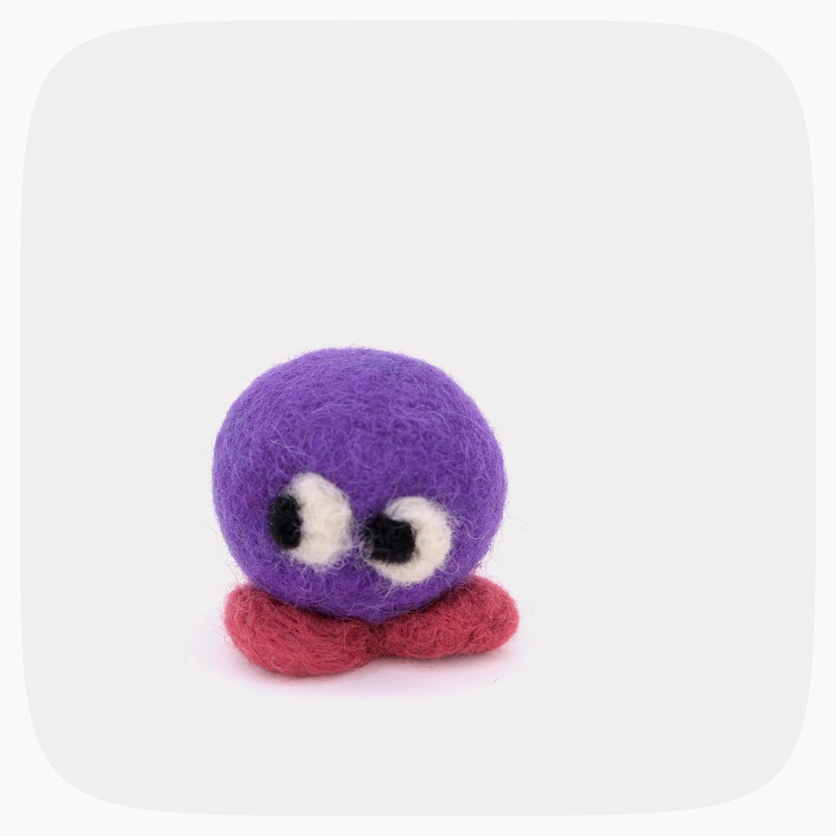A small felted wool creature toy with a round purple head, large white and black eyes, and a red feet, centered on a light gray background with rounded corners.
