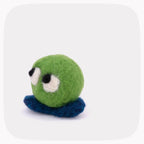 A small felted wool toy with a bright green round body, dark blue feet, and large white eyes with black pupils, centered on a light gray background with rounded corners.