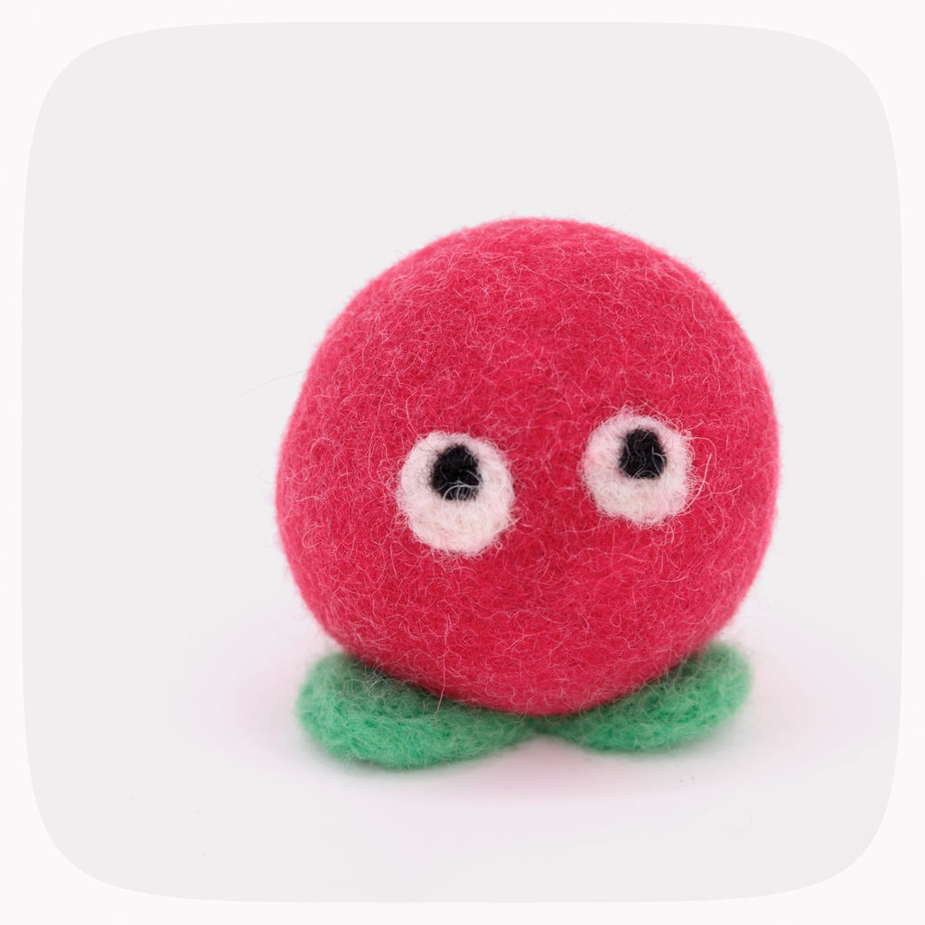 A red felted ball with eyes and light green feet.