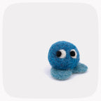 A small blue felted ball with eyes and light blue feet.
