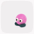 A small pink felted ball with eyes and green feet.