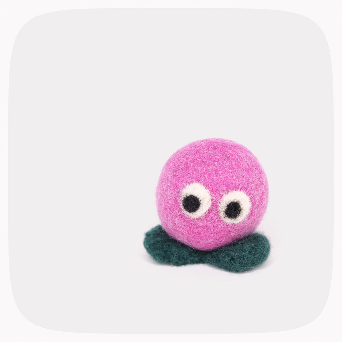 A small pink felted ball with eyes and green feet.