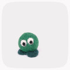 A small felted wool octopus toy in green with dark teal tentacles and large white-and-black googly eyes, centered on a light gray background with rounded corners.