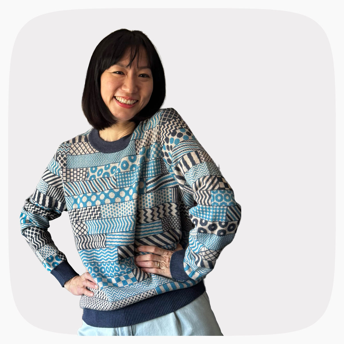 A woman wearing a blue and gray graphic knit sweater with several patterns across the garment.