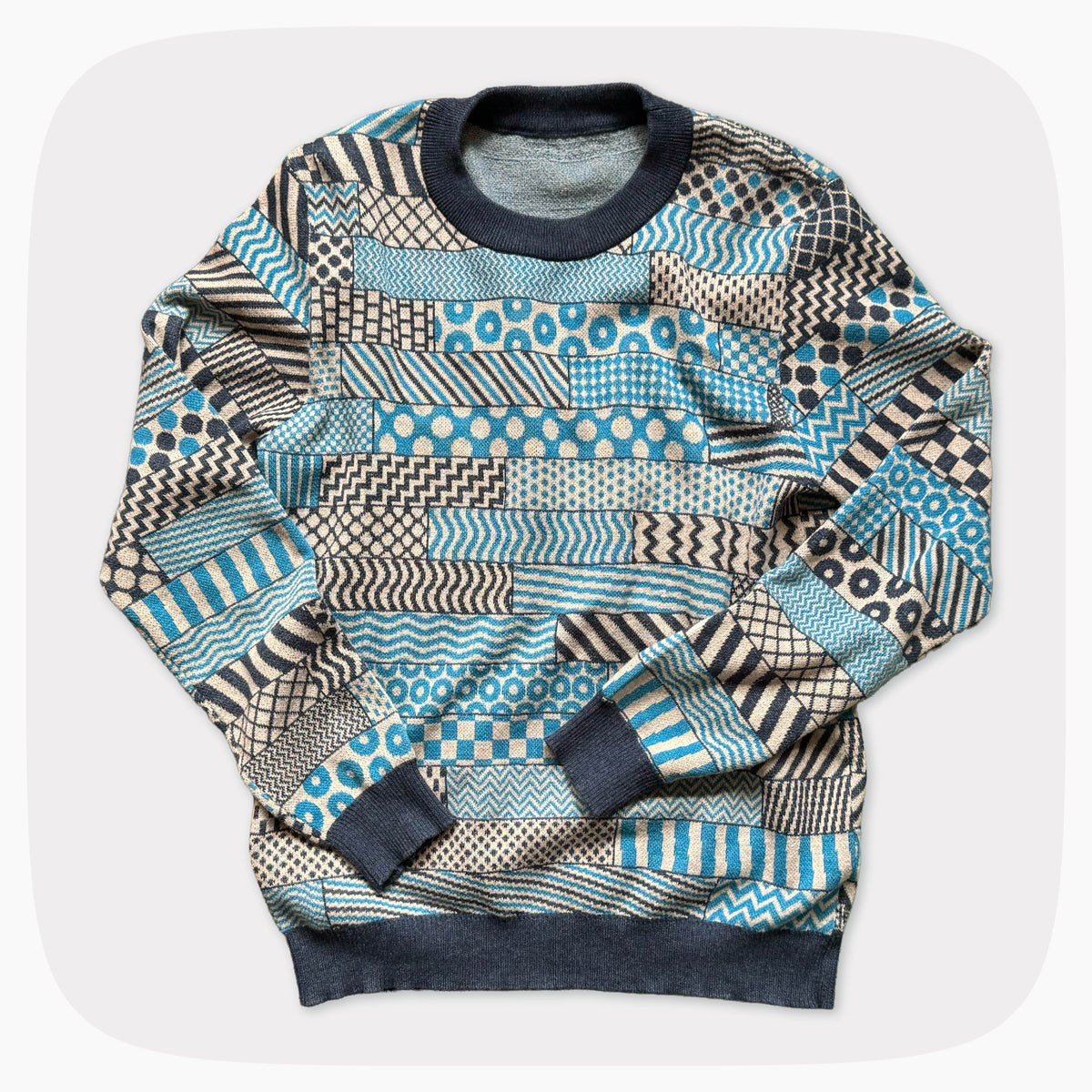 A blue and gray graphic knit sweater with several patterns across the garment.
