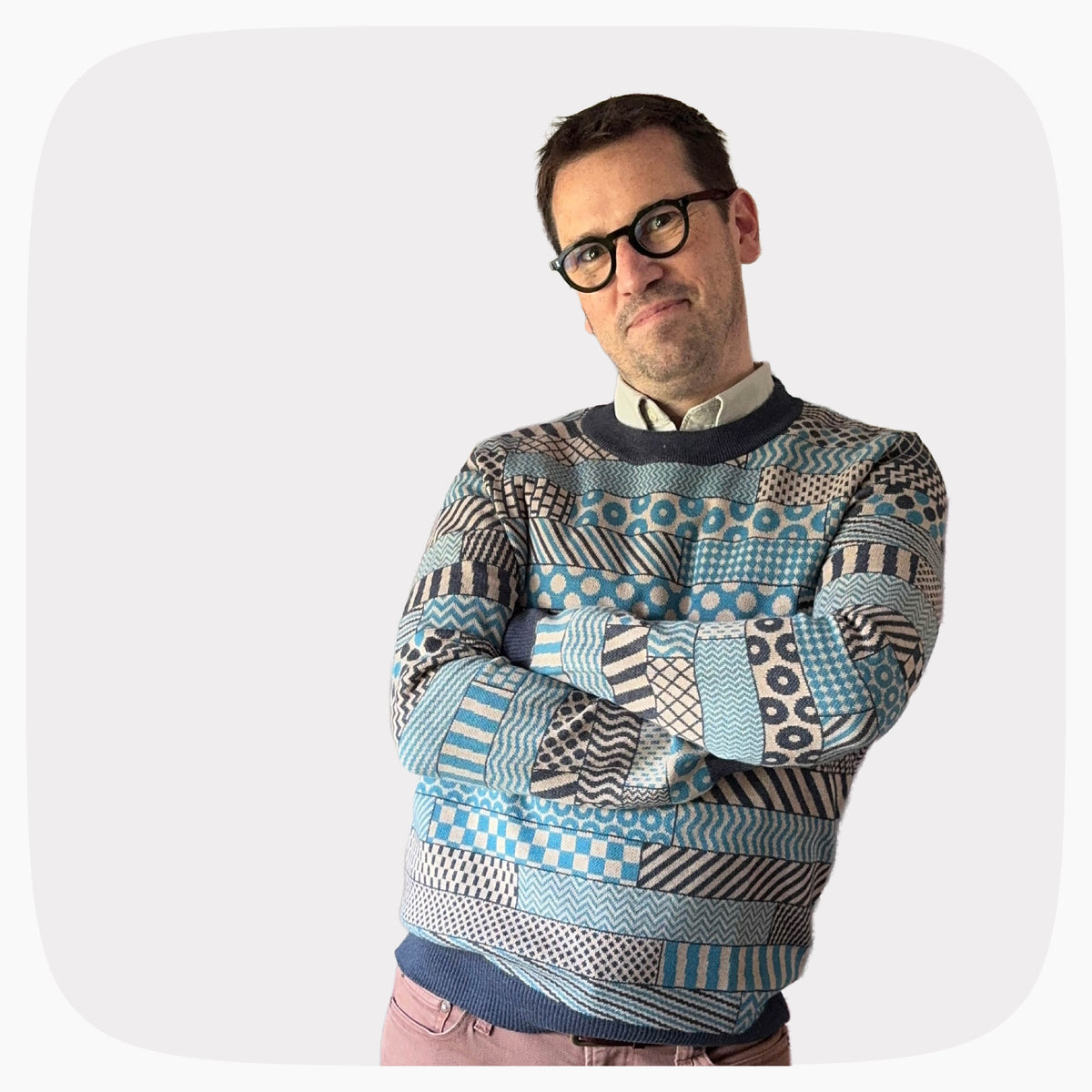 A man wearing a blue and gray graphic knit sweater with several patterns across the garment.