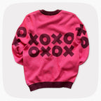 The back view of A pink graphic knit sweater with a dark red XOXO pattern across the chest.