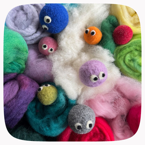 A close-up arrangement of colorful wool roving and small felted yarn balls with googly eyes, filling the frame on a rounded-square background.