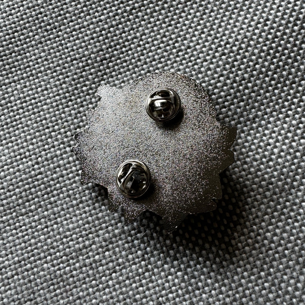 Detail of the back of an enamel pin with two pins and butterfly closures.