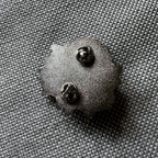 Detail of the back of an enamel pin with two pins and butterfly closures.